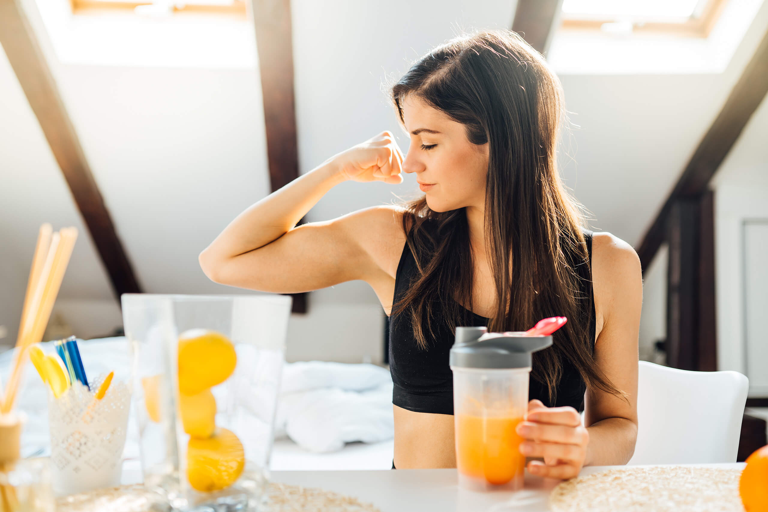 Woman at home drinking orange flavored vitamin Keto supplement After exercise for Immune system support
