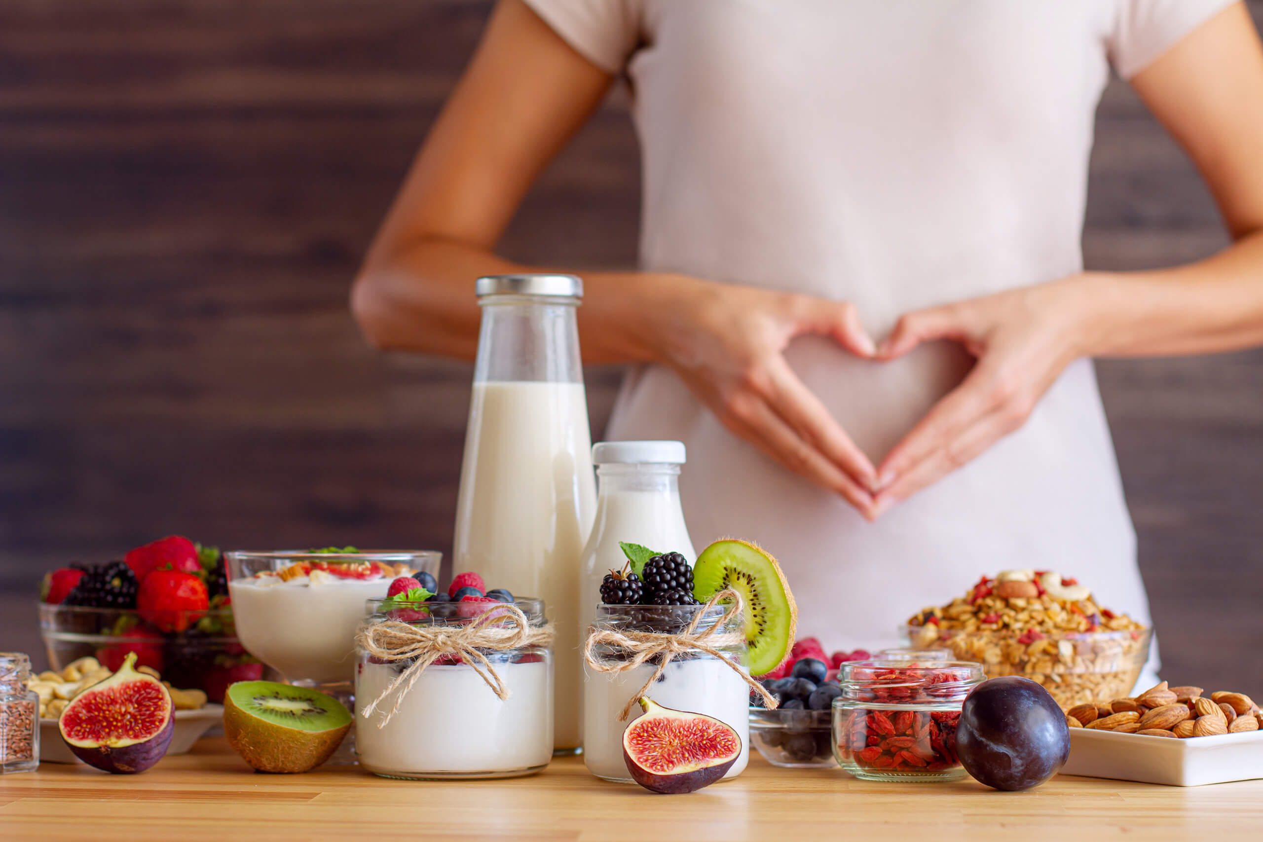 Female make shape of heart with her hands. Light summer breakfast with organic yogurts, fruits, berries and nuts. Nutrition that promotes good digestion and functioning of gastrointestinal tract.