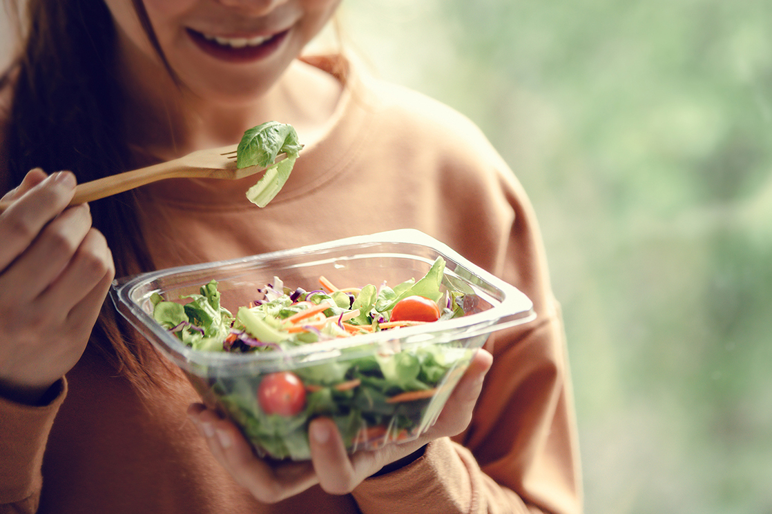 Closeup woman eating healthy food salad copy